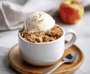 Delicious homemade apple crisp served in a mug with warm cinnamon and caramel apple slices