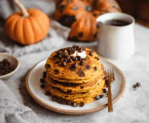Delicious pumpkin chocolate chip pancakes served with syrup on a plate, perfect for a cozy breakfast